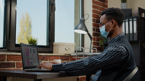 Side view of businessman wearing mask in office