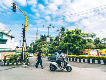 People riding motorcycle on road against sky