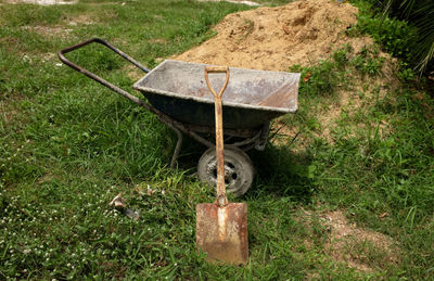 A cart for scooping sand on the green grass.