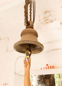 A human hand ringing a hanging bell of a temple on white background