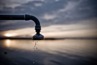 Water splashing in sea against sky during sunset