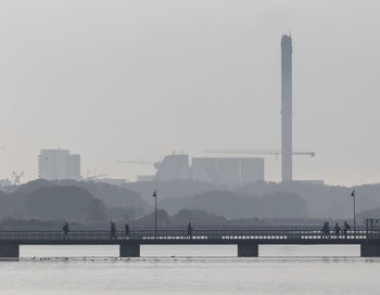 Bridge over river against sky during foggy weather