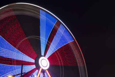 Low angle view of illuminated ferris wheel spinning at night