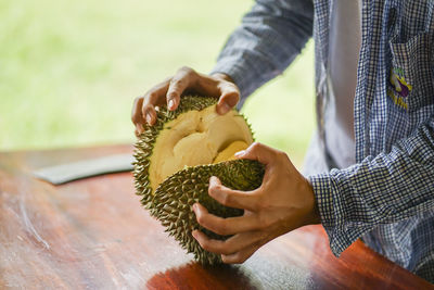 Midsection of man holding ice cream on table