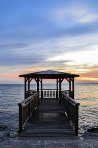 Pier over sea against sky during sunset