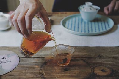 Midsection of man pouring tea cup on table