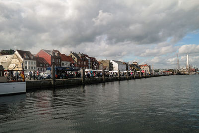 River by houses and buildings against sky