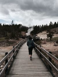 Rear view of man walking on footbridge