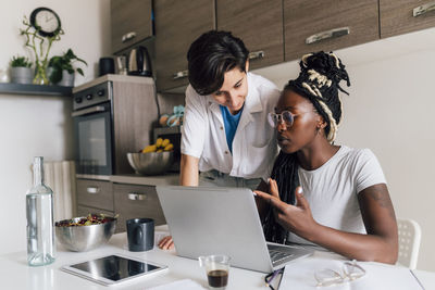 Young businesswoman discussing with colleague at home