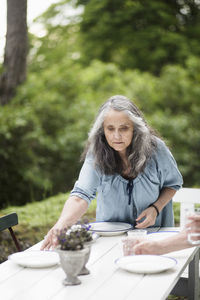 Senior couple arranging plates on table in back yard