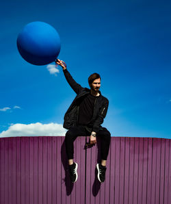 Low angle view of man with umbrella against sky