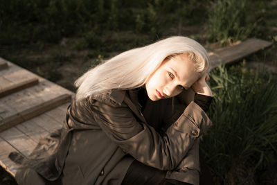 Portrait of beautiful young woman sitting on land in forest