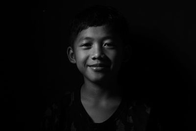 Portrait of smiling boy against black background