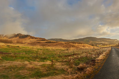 Scenic view of road amidst field against sky