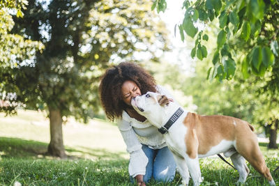 Happy mid adult woman with affectionate bulldog at park