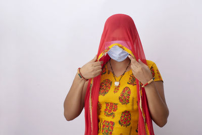 Close-up of woman wearing flu mask standing against white background