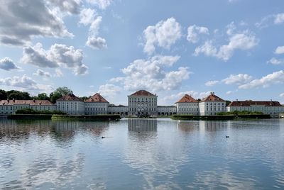 Buildings in lake against cloudy sky