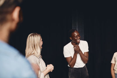 Happy young male artist with stage performers practicing in class