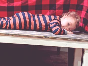 Portrait of boy lying on wooden floor