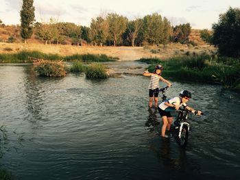 Boy with sister and bicycle standing in river