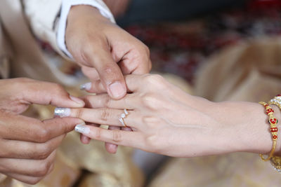 Cropped hand of groom holding bride fingers during wedding ceremony