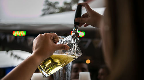 Cropped image of woman pouring beer from faucet at pub