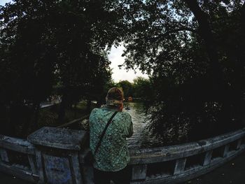 Rear view of woman standing by tree against sky