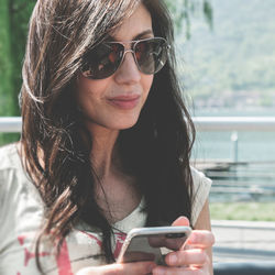 Close-up of woman wearing sunglasses using mobile phone