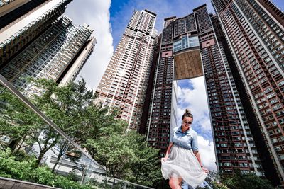 Low angle view of man standing by buildings against sky