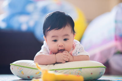 Cute baby girl lying on pillow at home