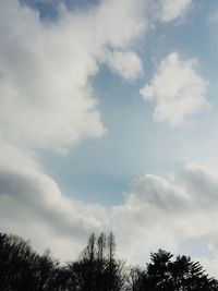 Low angle view of trees against cloudy sky