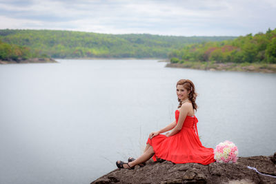 Young woman looking at shore against sky