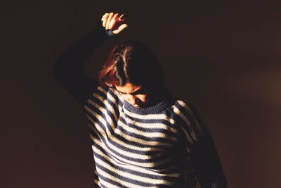 Mid adult woman standing against black background