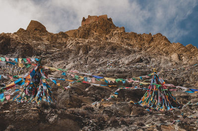 Multi colored flags on rocks against sky