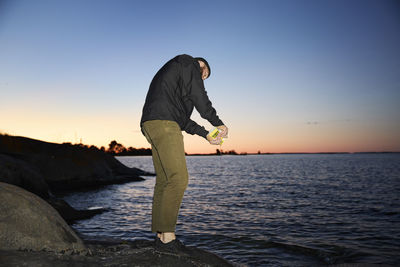 Man standing at sea at sunset