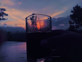 Close-up of beer glass against sunset sky