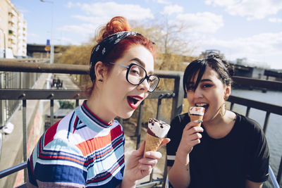 Portrait of hipster female friends eating ice cream in city