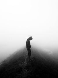 Side view of man standing on land against sky