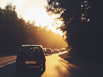 Cars on street against sky during sunset