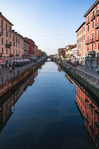 Canal amidst buildings against clear sky in city