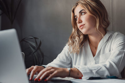 Portrait of young woman using laptop at office