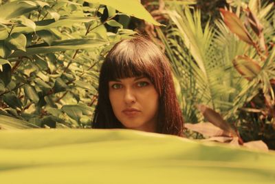 Portrait of beautiful young woman standing amidst plants