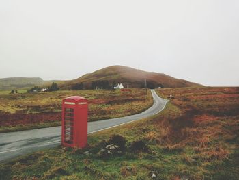 London style phone booth standing by the side of a country road.