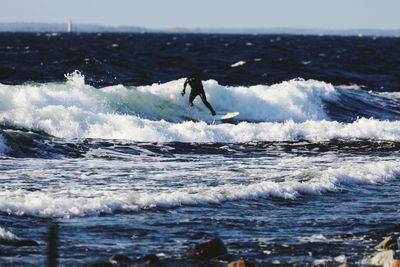 Man surfing in sea against sky