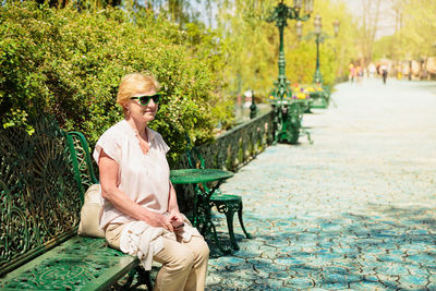 Mature beautiful woman traveler, sits on the bench of the park