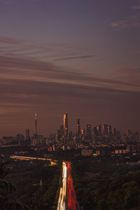 Illuminated cityscape against sky during sunset