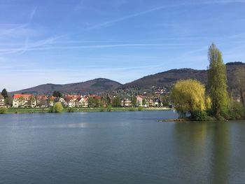 Scenic view of river by town against blue sky