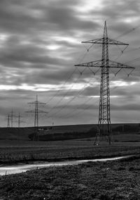 Low angle view of electricity pylon on field against sky