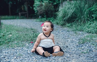 Cute boy looking away while sitting on land