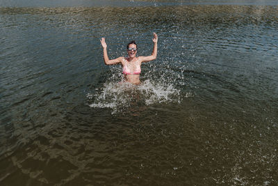 Cheerful woman splashing water in lake